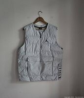Front full view of white Air Jordan vest hanging on wooden hanger, showing overall condition and design.