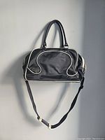 Front view of the black gym bag with white piping, handles, and shoulder strap visible.