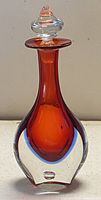 Front view of orange and clear Murano Sommerso bottle with stopper, showing bubble in bottom and shape of bottle
