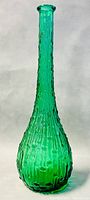 Front view of tall green textured glass decanter with narrow neck and flared rim.