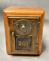 Front view showing brass combination lock door with window displaying '201' and wooden body.