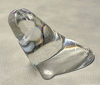 Close-up side view of the clear glass seal figurine showing smooth contours and facial details, displayed on a light surface.