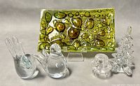 All items in the lot displayed on a flat surface including the multicolored art glass tray, blown glass Christmas tree on cracked acrylic stand, two blown glass birds, and a small glass candle holder.
