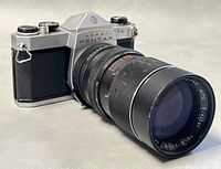 Asahi Pentax SP500 35mm film camera with attached Zoom Auto 85-200mm f/4.5 lens showing front-right angle.