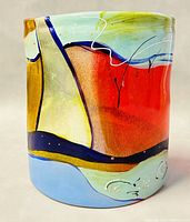 Front view of the fused glass vase showing a colorful abstract design with blues, reds, ochres, and white accents.