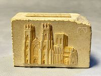 Front view of rectangular beige stone carved with detailed bas-relief of York Minster cathedral architecture with towers and windows.