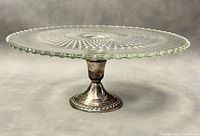Front angle view of vintage Candlewick cut glass cake plate on sterling silver pedestal base showing beaded rim and starburst pattern.
