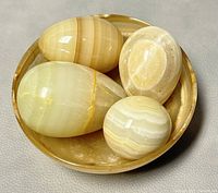 Photo of onyx bowl filled with four carved onyx eggs, showing bowl interior and eggs clustered inside