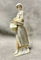 Front view of the Lladro porcelain figurine showing the woman holding a basket and chicken.