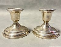 Front view of both Birks sterling silver candleholders showing the overall shape and rounded weighted bases.