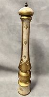 Full view of tall Florentine pepper mill showing its decorative paint and shape