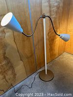 Full view of vintage floor lamp showing one arm extended horizontally with white conical shade illuminated.