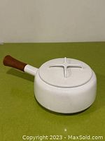 Side view of white Dansk pot with solid wood handle and lid in place.