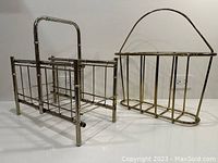 Two magazine racks side by side showing brass and steel construction with handles and bars