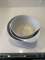 Top-down view of three white plastic mixing bowls nested inside each other on white countertop, showing the interior surfaces.