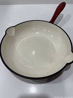 Top and inside view of the heavy cast iron skillet showing white enamel coating with small imperfection on interior surface.