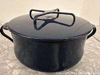 Navy blue round enamel pot with lid and side handles.