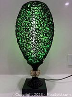 Front angled view of the green inner shade lit lamp with black resin string outer shade, showing general shape and details.