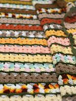 Close-up view of the detailed hand crocheted multi-colored stitches and dark olive separating rows, showing the texture and color variety.