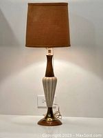 Full view of the Mid-Century Modern lamp showing its tall silhouette with ceramic body, wooden neck, brass base, and brown textured shade.