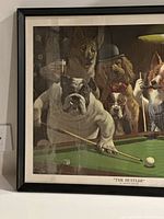 Framed print showing bulldog aiming at pool ball on billiards table with other dogs watching