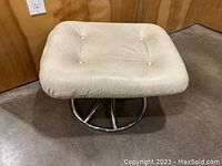 Front and top view of the vintage cream leather ottoman showing the cushion with button tufting on a circular chrome swivel base.