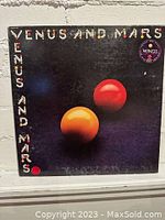 Front cover of 'Venus and Mars' vinyl showing black background with orange and red spheres and colorful text.