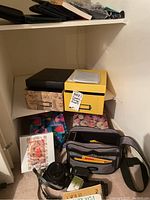 Lot contents including padded camera bag, photo storage boxes, and photographic accessories on a carpeted floor.