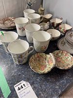 Overview photo showing various cups, bowls, and plates with floral patterns on a countertop.