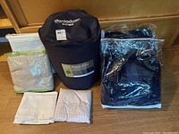 Wide shot showing duvet in carry bag, blankets, and pillowcases laid out on wooden floor.