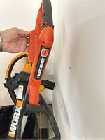 Close-up of Black+Decker orange and black electric garden blower/vacuum showing brand label and handle.