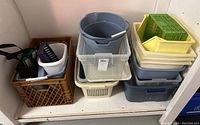 Overall view of stacked plastic storage totes, buckets, trays, and crate with bags inside