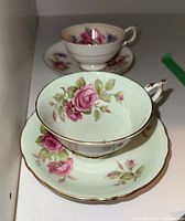 Front angled view of the teacup with floral design inside and matching saucer beneath, showing gold trim and scalloped edges