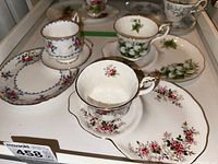 Photo of several Royal Albert teacups with different floral patterns placed on matching saucer plates inside a display case.
