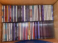 Two rows of CDs neatly lined inside an open box showing spines with various musical and soundtrack titles.