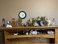 Photo of assorted figurines and decorative items arranged on wooden shelf with some items in lower compartments.