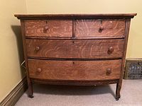 Front view of vintage wooden dresser showing four wood knobbed drawers with signs of wear and keyholes without keys.
