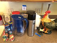 Full view of the lot displaying jars, canisters, rooster items, Brita pitcher and filters, and thermos