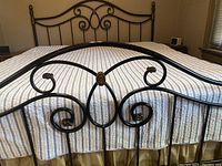 Front view detail of metal bed frame footboard with black finish and decorative scrolls.
