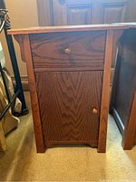 Front view of wooden nightstand showing drawer and cabinet door with round wooden knobs.
