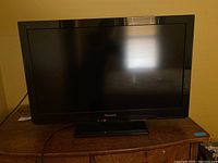 Front view of Panasonic flat screen TV powered off, showing overall condition and screen size.