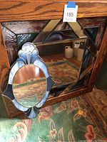 Two hanging mirrors with stained glass surrounds placed on carpet, one larger and one smaller mirror visible