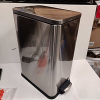 Angle showing front and lid with foot pedal of the polished steel garbage can