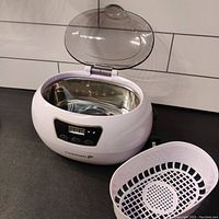 Open ultrasonic jewelry cleaner showing the stainless steel inner cleaning chamber and white removable plastic basket