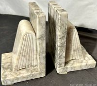 Side angle view of the pair of alabaster bookends showing veined texture and carved book page details.