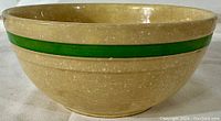 Exterior side view of yellowware mixing bowl showing green band and speckled glaze.