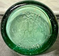 Close-up of bottom of bottle showing embossed Pluto cartoon character and brand name 'PLUTO'.