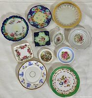 Top-down photo showing 10 porcelain plates in various shapes and floral patterns, some with cobalt blue and gold trim.