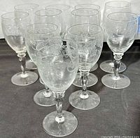 Front view of 11 clear Bohemia crystal wine glasses with etched thistle pattern.