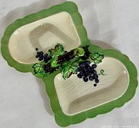 Top view of the divided ceramic serving dish showing the grape and leaf embossed detail and green border with cream interior.
